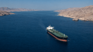 Oil tanker traveling through the Strait of Hormuz between rugged desert coastlines