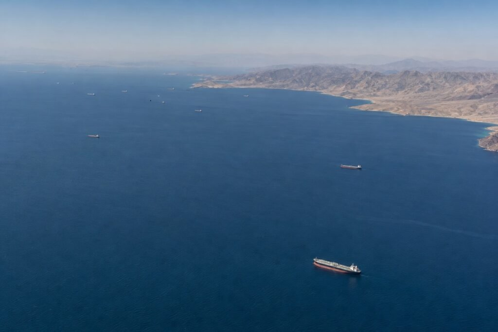 Overhead aerial view of oil tanker traffic moving through the Strait of Hormuz, illustrating global energy supply routes and geopolitical risk.